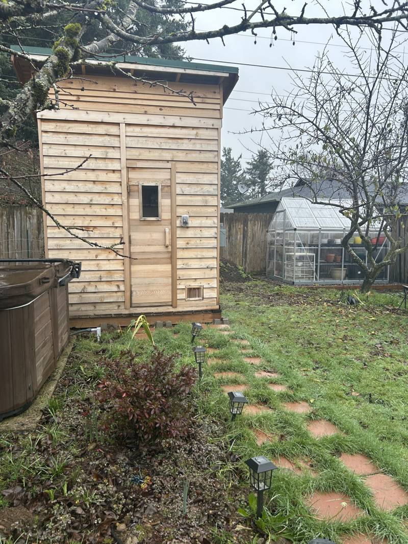 backyard sauna with a red paver path nestled in the grass